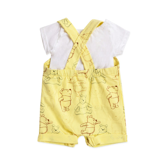 yellow sleeveless salopette with winnie the pooh print and a white top